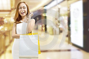 Cheerful asian woman carrying shopping bags in mall