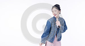 Cheerful asian woman holding microphone in own hands enjoyment sing song while standing over isolated white background. Lifestyle