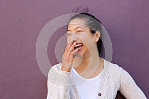 Cheerful asian woman laughing with hand on mouth