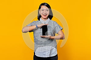 Cheerful asian woman showing blank smartphone screen with palm. product promotion concept