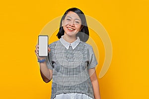 Cheerful asian woman showing blank smartphone screen with palm. product promotion concept