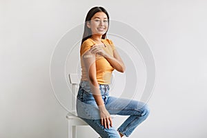 Cheerful Asian woman showing shoulder with adhesive bandage after coronavirus vaccine injection on white background