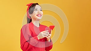 Cheerful asian woman using smartphone and rejoice over yellow background