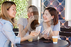 Cheerful asian young women sitting in cafe drinking coffee with friends and talking together.