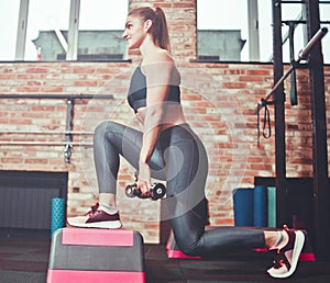 Cheerful athlete woman doing lunges with dumbbells