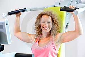 Cheerful athletic woman using weight machine