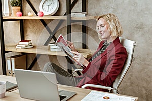 Cheerful attentive woman resting on white office armchair