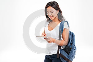 Cheerful attractive asian girl with backpack making notes in notebook