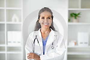 Cheerful attractive mature lady doctor posing at clinic
