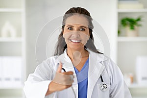 Cheerful attractive mature lady doctor showing thumb up