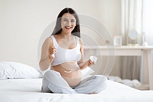 Cheerful attractive pregnant woman massaging her big belly