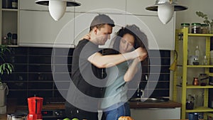 Cheerful and attractive young couple in love dancing together funky dance in the kitchen at home on holidays