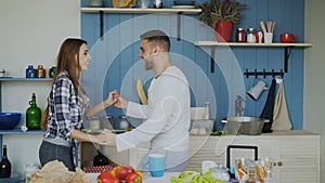 Cheerful and attractive young couple in love dancing together latin dance in the kitchen at home on holidays