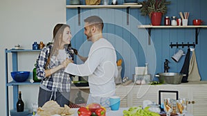 Cheerful and attractive young couple in love dancing together latin dance in the kitchen at home on holidays