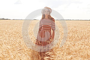 Cheerful attractive young woman standing straight in filed at rural area, feeling nature, being inspired with landscape, having