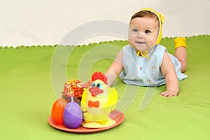 The cheerful baby with an easter entertainment on a green background