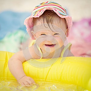 Cheerful baby girl with Downs Syndrome playing in the pool