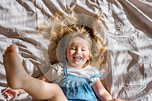 Cheerful baby laughing. cheerful girl lies on the bed and screams with joy
