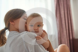 Cheerful baby in mother's embrace. Family moments