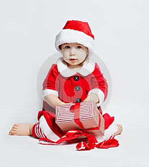 Cheerful baby in Santa hat opening Christmas gift box