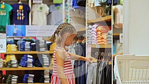 Cheerful baby shopper customer is looking and buying casual clothes in clothing store.Cute shopaholic little child