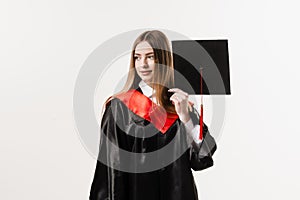 Cheerful bachelor girl in graduation robe and cap on white background. Happy and funny young woman smile. Student