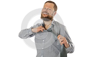 Cheerful bearded man dressed in shirt rips off his tie