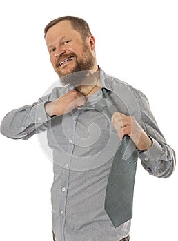 Cheerful bearded man dressed in shirt rips off his tie