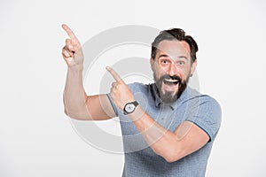 Cheerful bearded man pointing to the upper left part of the photo