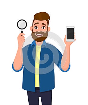 Cheerful bearded young man holding magnifying glass and mobile, cell, smart phone in hand. Search, find, discovery, analyze.