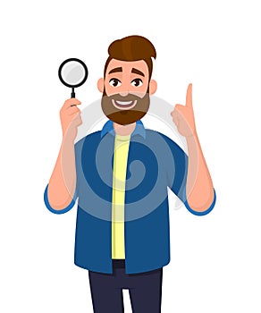 Cheerful bearded young man holding/showing magnifying glass and pointing hand finger up. Search, find, discovery, analyze, inspect