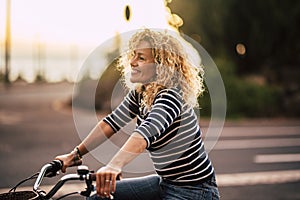 Cheerful beauiful blonde curly caucasian woman smile and enjoy the ride on a bike in outdoor leisure activity in the city - free