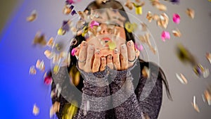 Cheerful beautiful brunette girl blowing confetti from her hands. Celebration of the holiday. Festive New Year&#s
