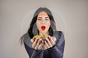 Cheerful beautiful brunette girl blowing confetti from her hands. Celebration of the holiday. Festive New Year&#s