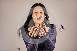 Cheerful beautiful brunette girl blowing confetti from her hands. Celebration of the holiday. Festive New Year& s