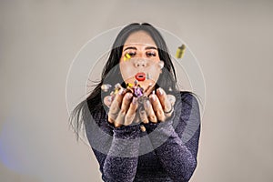 Cheerful beautiful brunette girl blowing confetti from her hands. Celebration of the holiday. Festive New Year& s