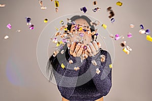 Cheerful beautiful brunette girl blowing confetti from her hands. Celebration of the holiday. Festive New Year& s