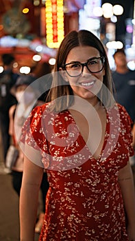 Cheerful beautiful hispanic woman in glasses posing on famous dotonbori street in osaka, enjoying the city lights at night with a