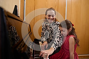 Cheerful beautiful woman pianist, musician teacher smiling while performing melody on piano, explaining music lesson to
