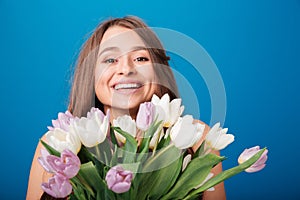 Cheerful beautiful woman smiling and holding bouquet of spring flowers