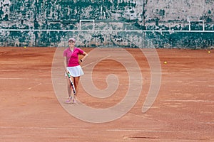 Cheerful beautiful woman in sportswear, standing on the court with tennis racket, looking at camera. Sport concept