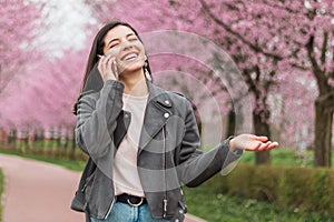 Cheerful beautiful woman with wide and beautiful smile on the phone with a beloved walking in the park
