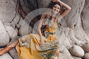 Cheerful beautiful young boho style model on the stone beach