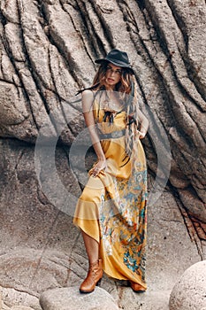 Cheerful beautiful young boho style model on the stone beach