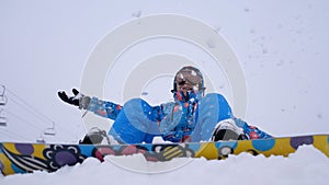 Cheerful beautiful young girl snowboarder throws snow flakes. Winter fun at the ski resort.