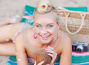 Cheerful beautiful young woman lying on the beach with vintage c