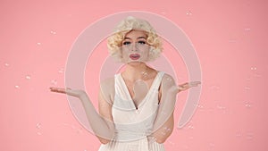 Cheerful beautiful young woman surrounded by soap bubbles. Woman looking like Marilyn Monroe in studio on pink