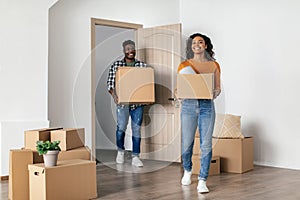 Cheerful Black Couple Entering New House Carrying Moving Boxes Indoor