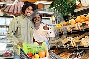 Cheerful Black Couple On Grocery Shopping Gesturing Thumbs-Up In Supermarket