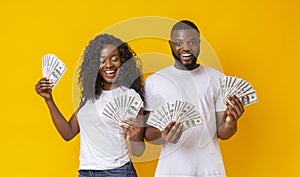 Cheerful black couple holding money and smiling